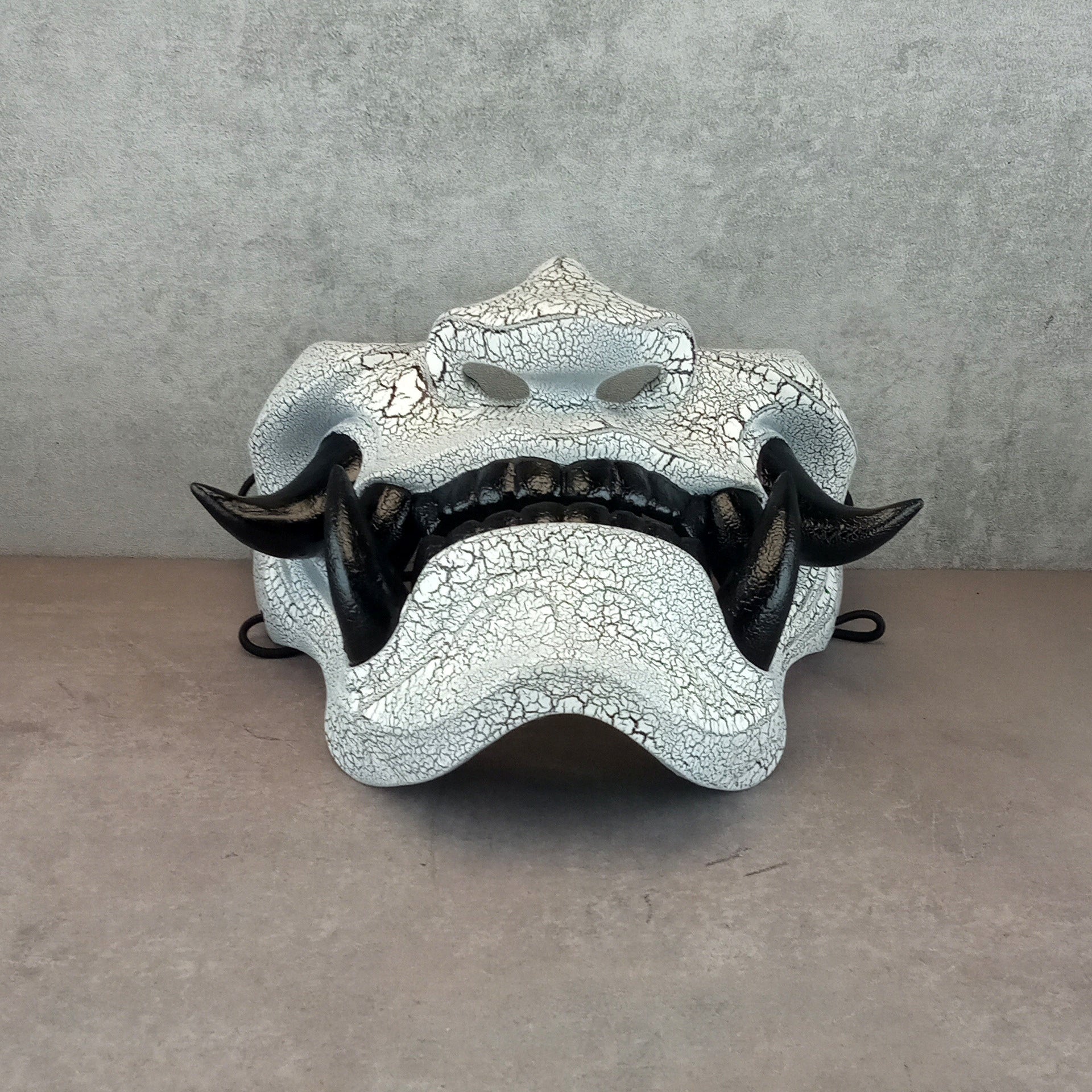 Schwarz-weiße rissige Samurai-Maske mit schwarzen Reißzähnen