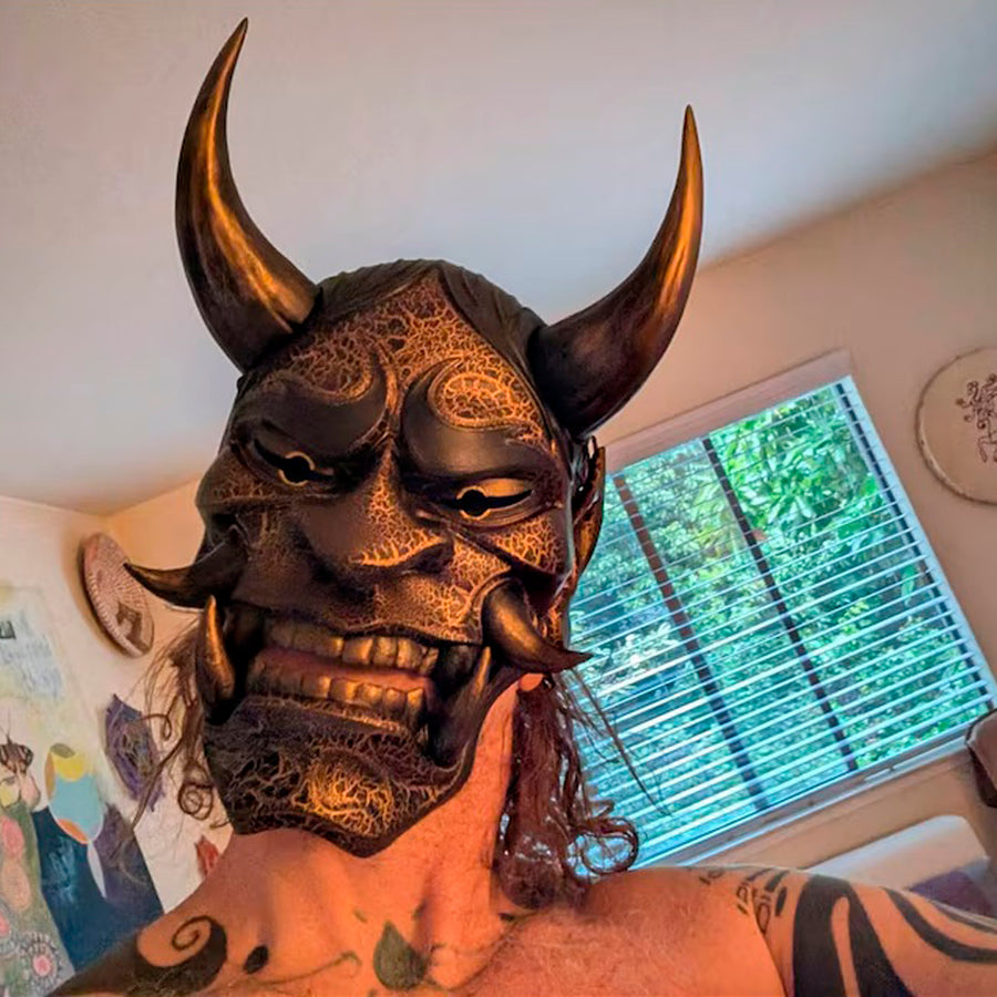 Schwarze und goldene rissige traditionelle Hannya-Maske mit großen schwarzen Augenbrauen