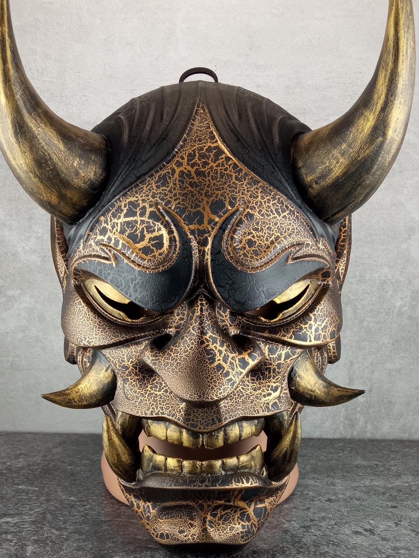 Schwarze und goldene rissige traditionelle Hannya-Maske mit großen schwarzen Augenbrauen