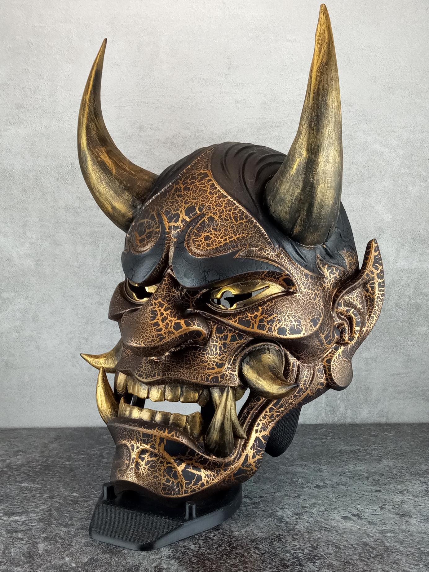 Schwarze und goldene rissige traditionelle Hannya-Maske mit großen schwarzen Augenbrauen