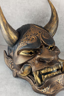 Schwarze und goldene rissige traditionelle Hannya-Maske mit großen schwarzen Augenbrauen