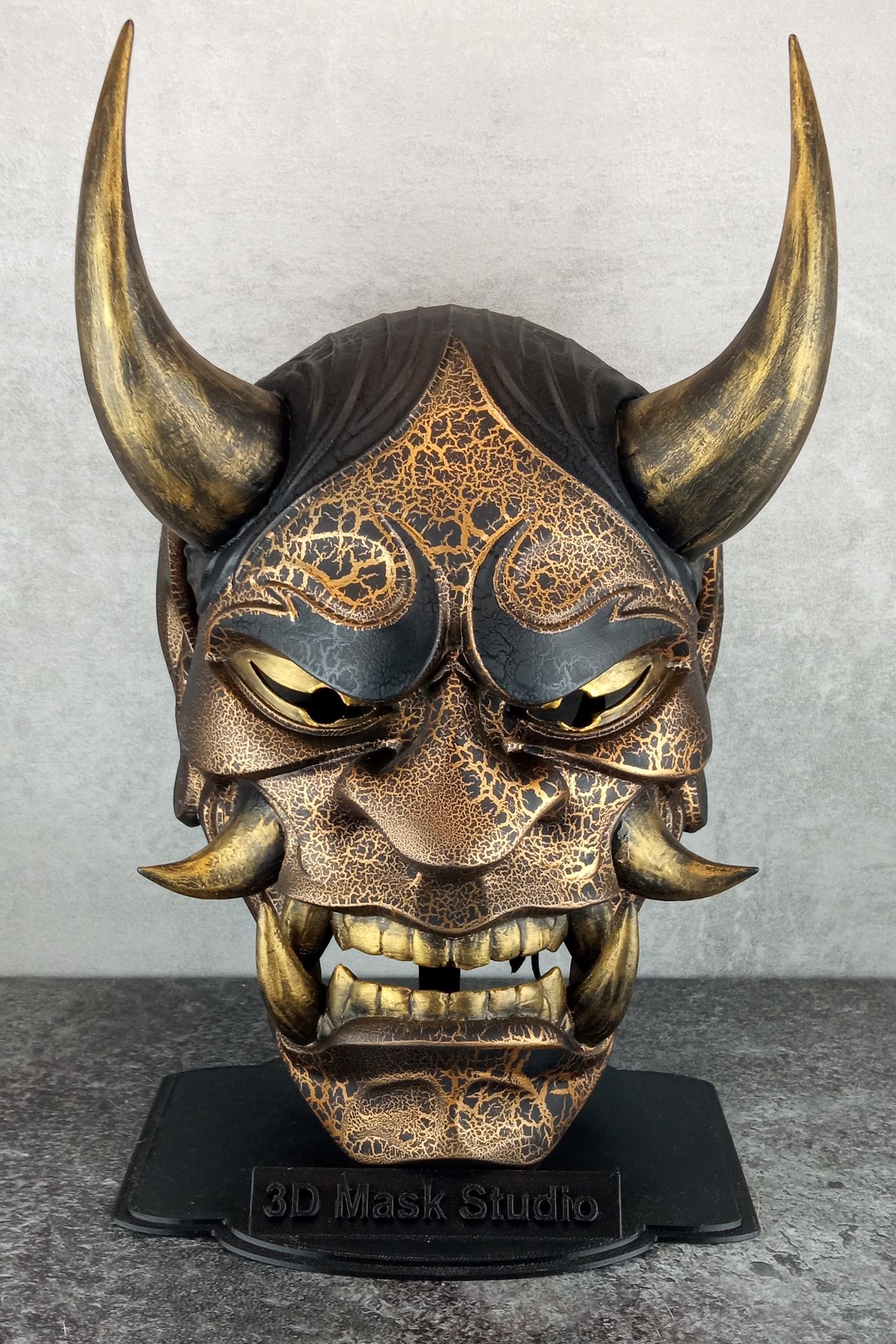 Schwarze und goldene rissige traditionelle Hannya-Maske mit großen schwarzen Augenbrauen