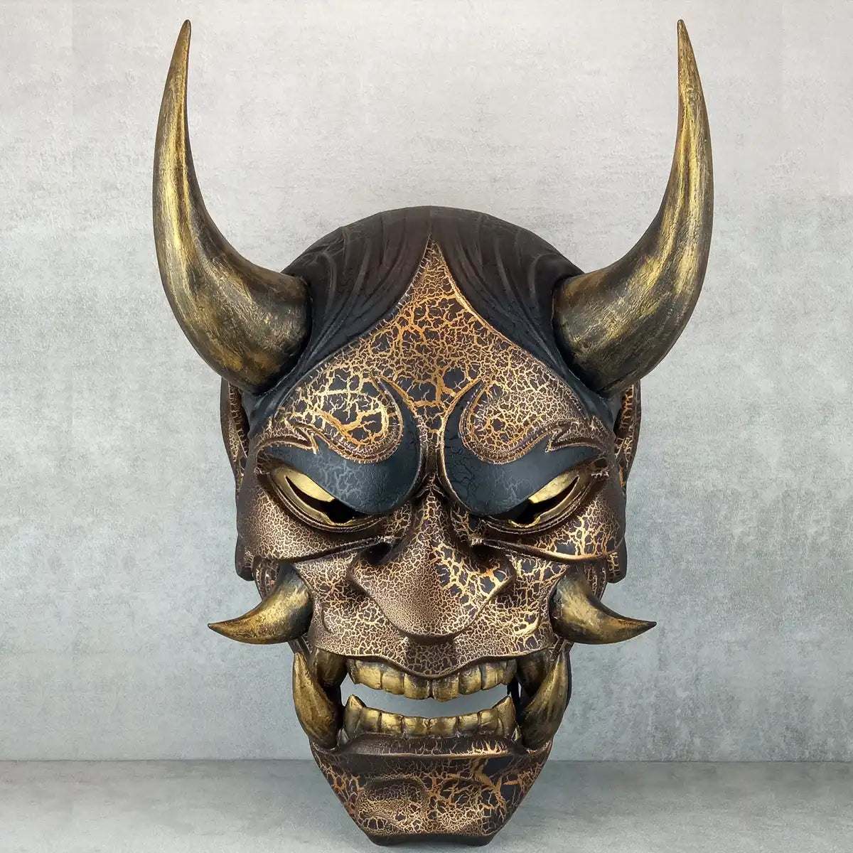 Schwarze und goldene rissige traditionelle Hannya-Maske mit großen schwarzen Augenbrauen