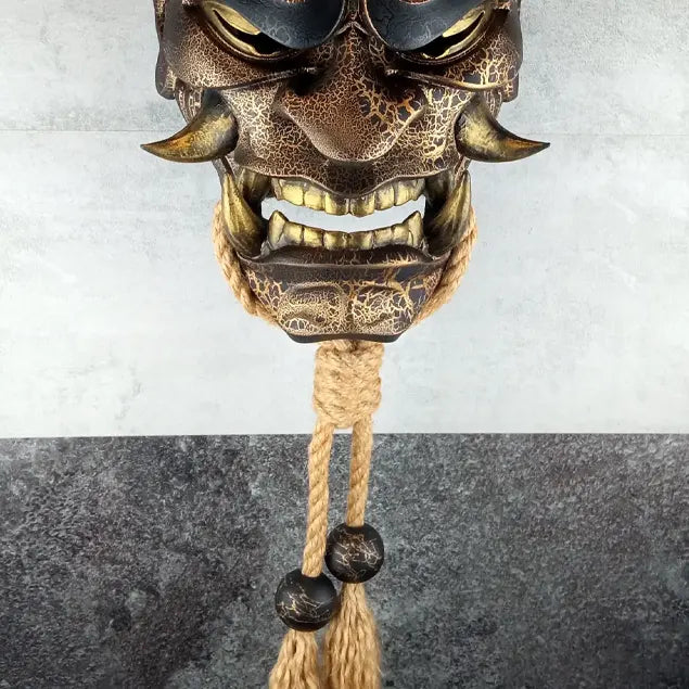 Schwarze und goldene rissige traditionelle Hannya-Maske mit großen schwarzen Augenbrauen