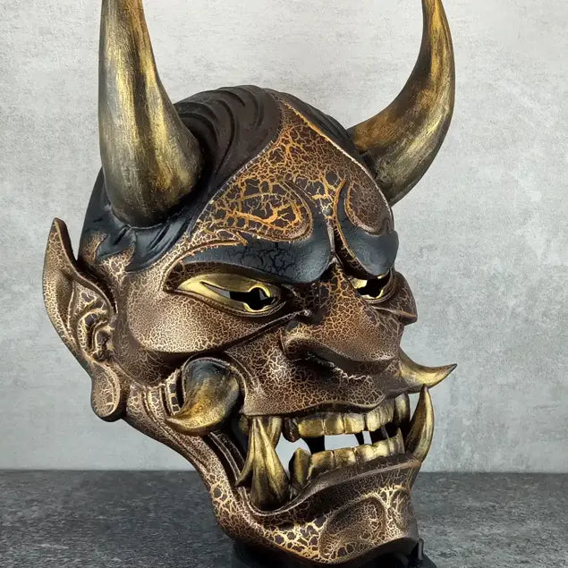 Schwarze und goldene rissige traditionelle Hannya-Maske mit großen schwarzen Augenbrauen