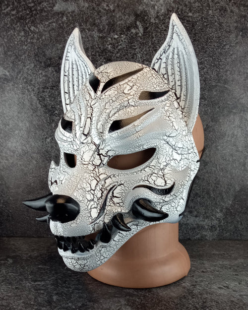 Schwarz-weiße rissige Kitsune (Okami)-Maske mit schwarzen Reißzähnen