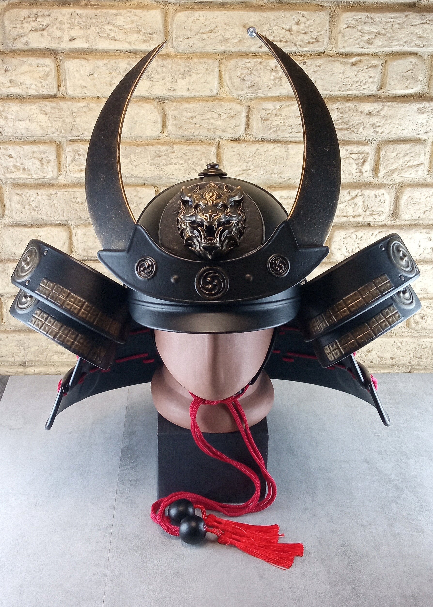 Schwarzer Samurai-Kabuto-Helm mit bronzenen Akzenten und zentralem Oni-Tiger-Emblem