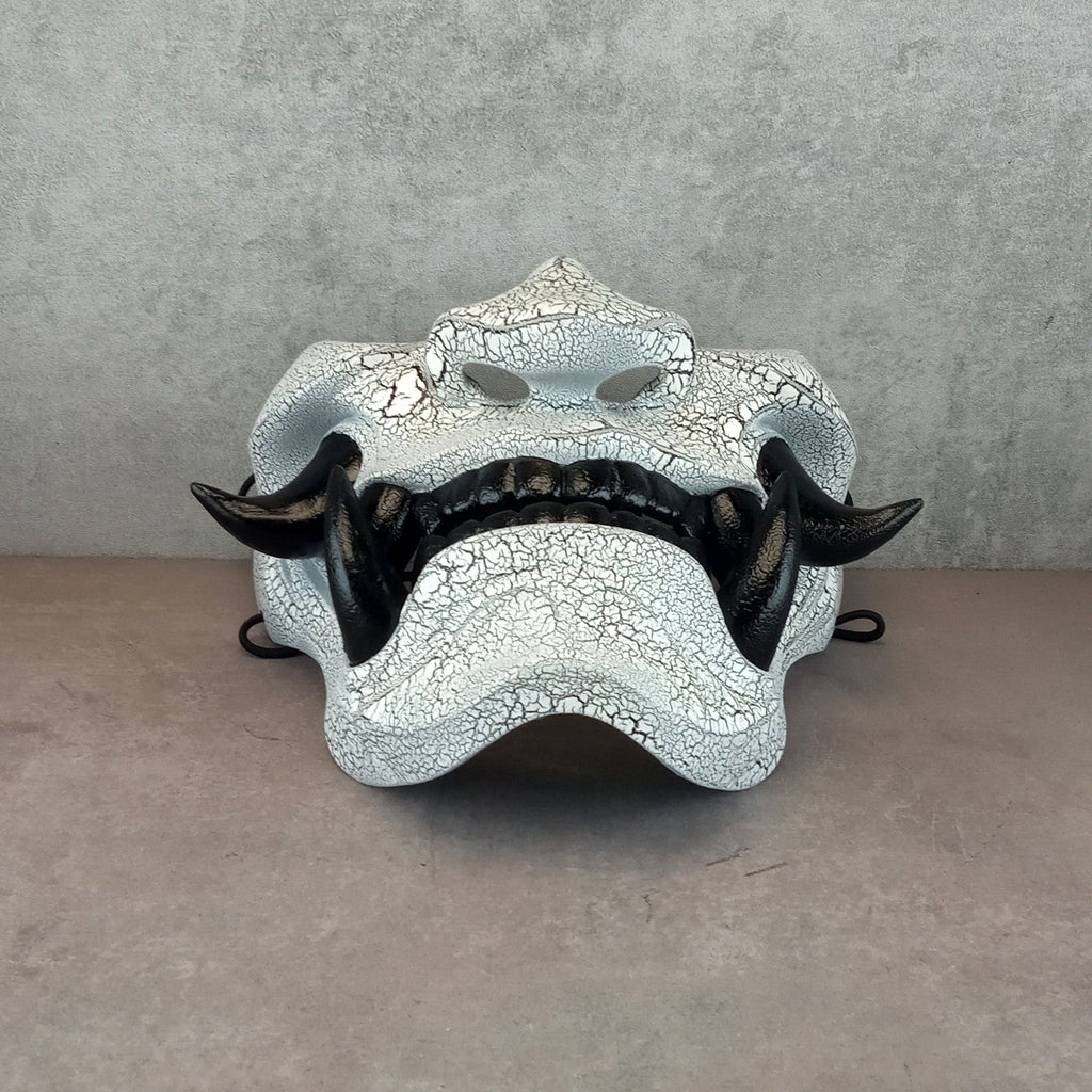 Schwarz-weiße rissige Samurai-Maske mit schwarzen Reißzähnen