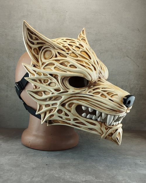 A detailed, 3D-printed wolf mask with intricate cutout patterns, displayed on a mannequin head against a gray concrete-textured background.