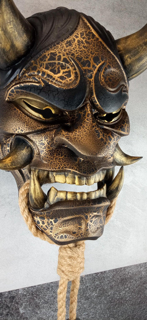 Schwarze und goldene rissige traditionelle Hannya-Maske mit großen schwarzen Augenbrauen