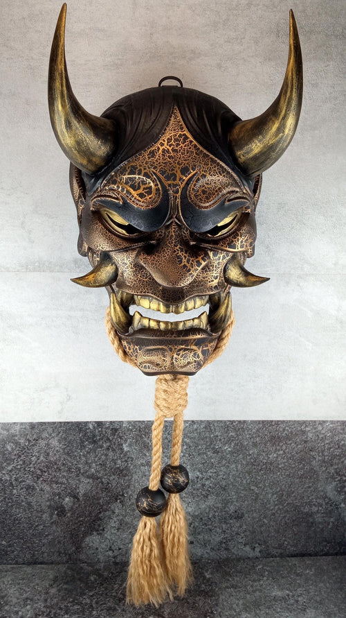 Schwarze und goldene rissige traditionelle Hannya-Maske mit großen schwarzen Augenbrauen