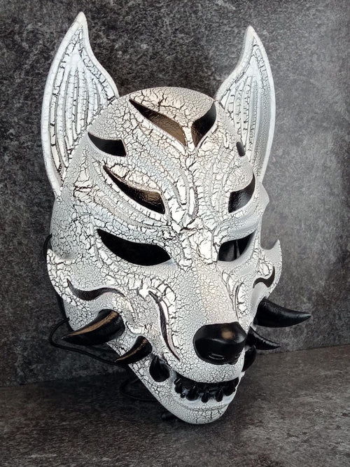 Schwarz-weiße rissige Kitsune (Okami)-Maske mit schwarzen Reißzähnen