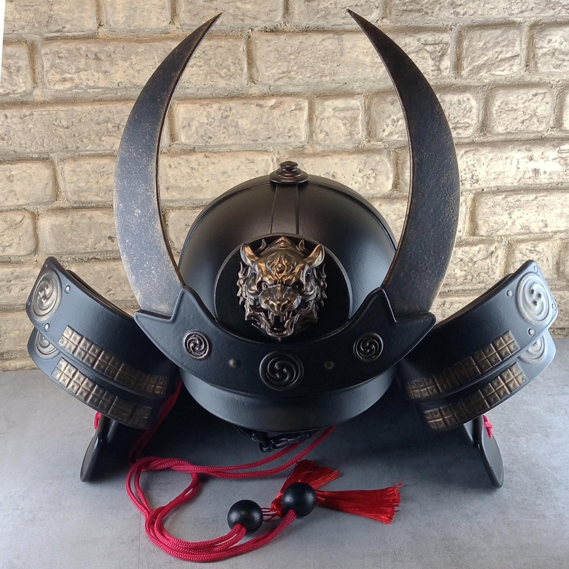 Schwarzer Samurai-Kabuto-Helm mit bronzenen Akzenten und zentralem Oni-Tiger-Emblem