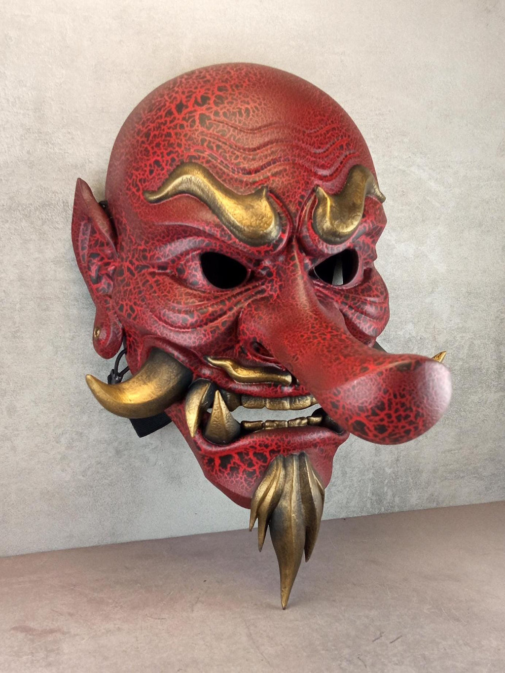 Rote, gesprungene Tengu-Dämonenmaske mit goldenen Reißzähnen