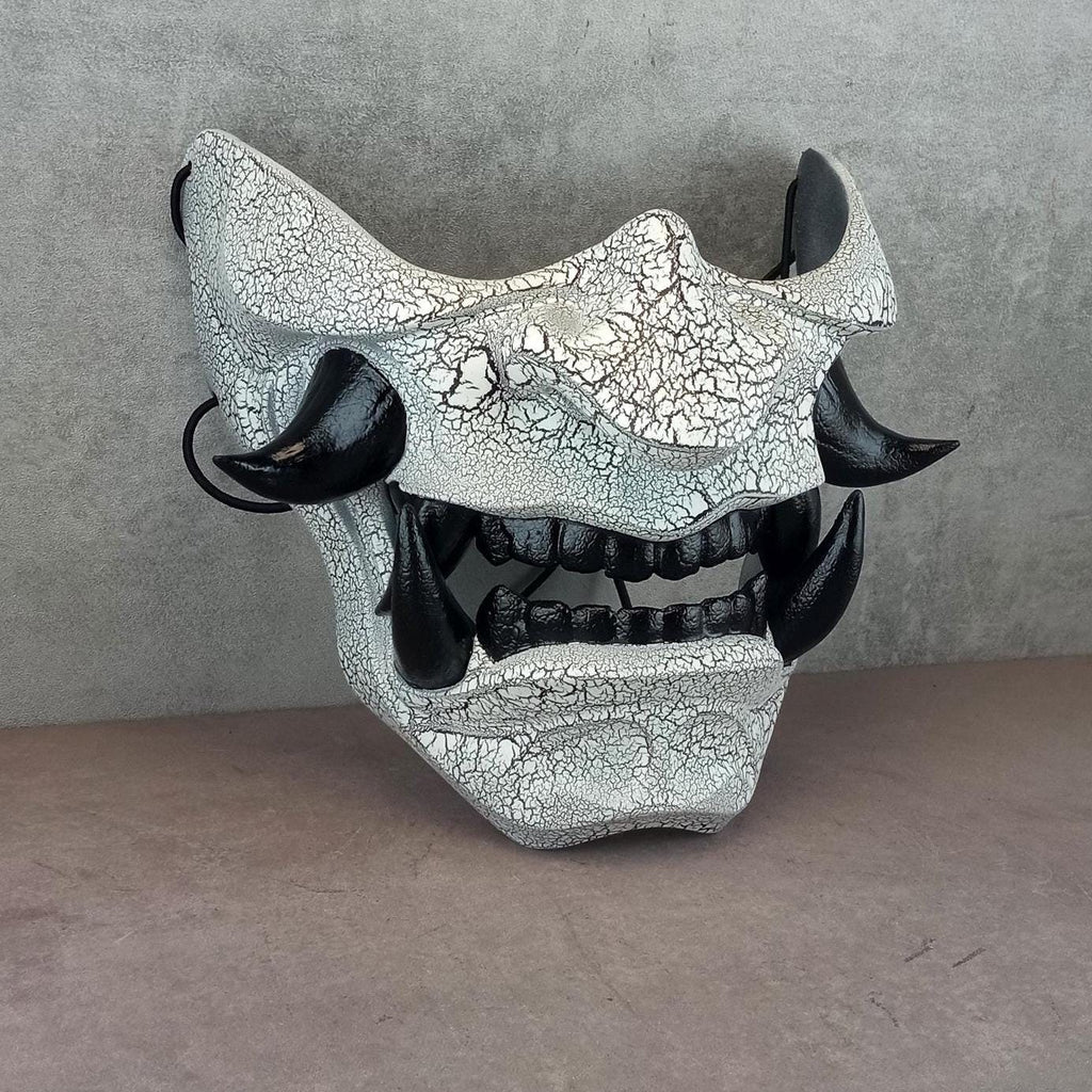 Schwarz-weiße rissige Samurai-Maske mit schwarzen Reißzähnen